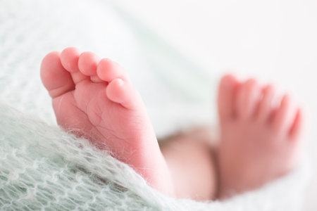 Feet of newborn baby wrapped in a knitted blanket, closeup