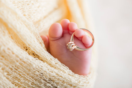 Newborn baby's foot with a wedding ring on a white backgroundの写真素材