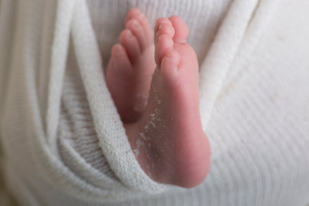 Feet of a newborn baby wrapped in a white blanket close-upの写真素材