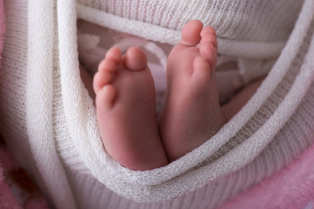 Feet of a newborn baby wrapped in a white blanket, close-upの写真素材