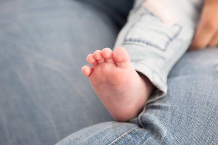 Newborn baby feet on blue jeans background. Selective focus.の写真素材
