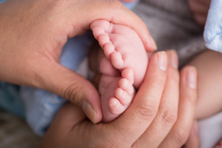 Mother holding her newborn baby feet. Close up of mother's hands holding newborn baby feet.の写真素材