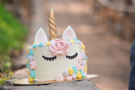 Unicorn cake decorated with buttercream and pink roses on wooden backgroundの写真素材