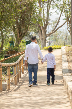 Back view of father and son walking on the bridge in the parkの写真素材