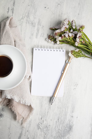Cup of coffee, blank notepad and flowers on wooden backgroundの写真素材