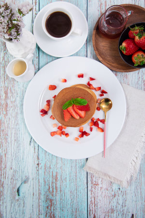 pancakes with strawberries and honey on a wooden background, top viewの写真素材