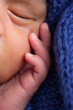 Newborn baby boy sleeping on a blue knitted blanket, closeupの写真素材
