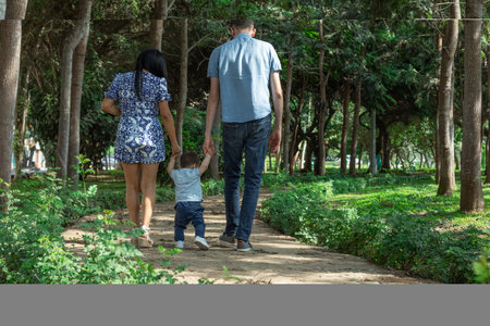 Back view of happy family walking in the park. Father, mother and childの写真素材