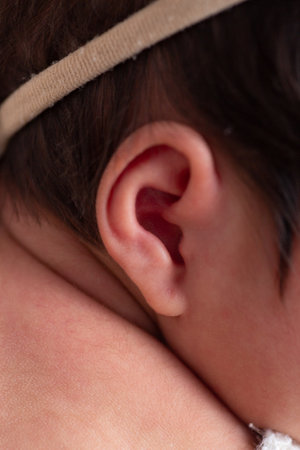 Closeup of the ear of a newborn baby wearing a headbandの写真素材