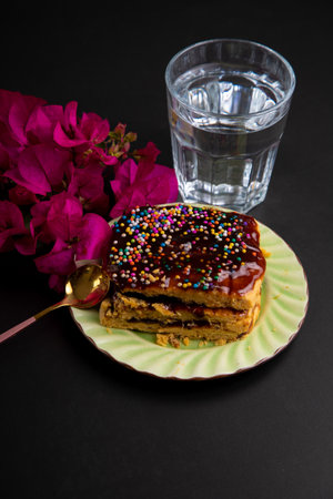 Chocolate cake and a glass of water on a black background.
