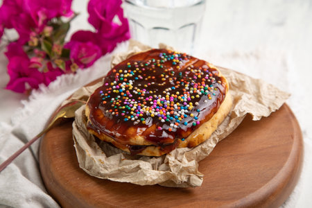 Tasty chocolate tart with colorful sprinkles on wooden board, closeup