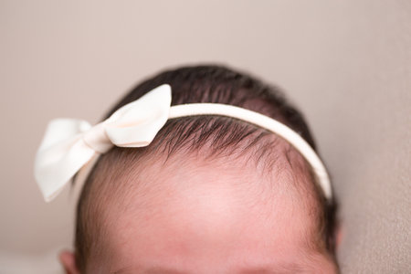 Newborn baby girl with a white bow on her head. Close-up.の写真素材