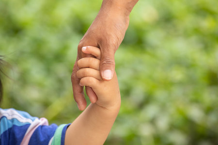 Close up of father holding hand of his daughter in nature background.の写真素材