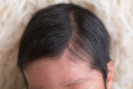 close up of newborn baby face with black hair on white background.の写真素材