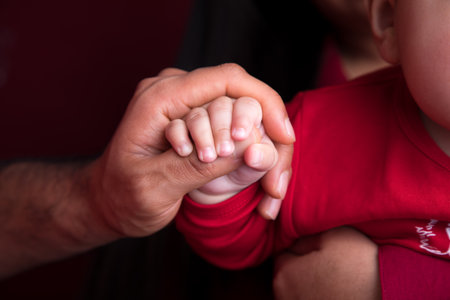 Close-up of father holding hand of his little daughter, shallow depth of fieldの写真素材