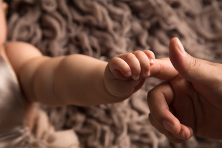 Mother holding her baby's hand on knitted background, closeupの写真素材