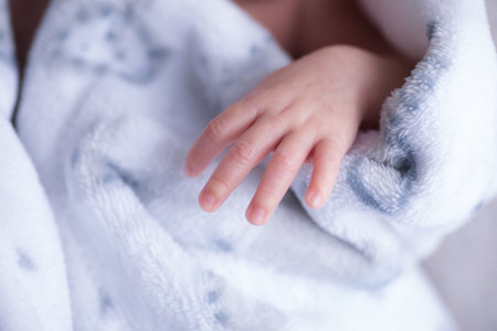 Newborn baby hand in blue blanket close-up. Shallow depth of field