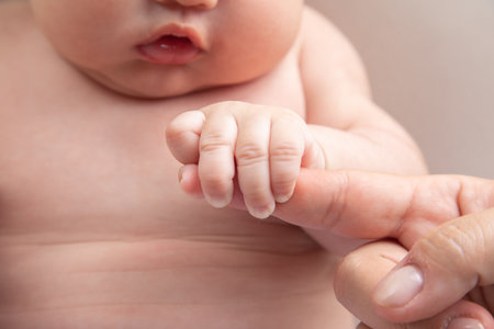 Newborn baby's hand holding mother's finger, close up shotの写真素材