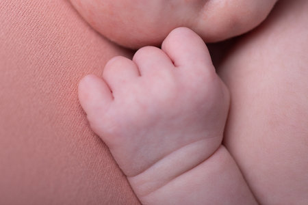 Close-up of a baby's hand on a pink background.の写真素材