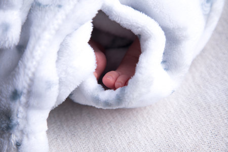 Newborn baby wrapped in a blue towel on a white background.