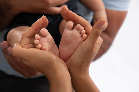 Mother and father holding baby's feet on white background, closeupの写真素材