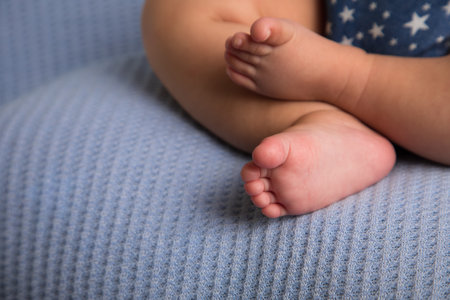 Newborn baby feet on a blue background, close-up.の写真素材