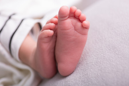 Newborn baby feet on bed, closeup. Baby care conceptの写真素材