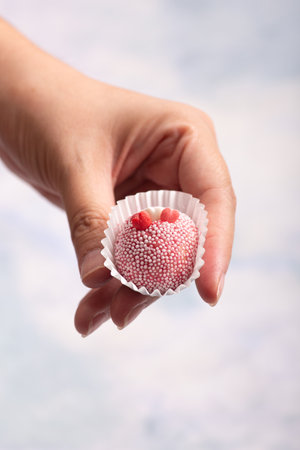 Hand holding a strawberry on a blue background with copy spaceの写真素材