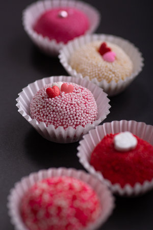 Brazilian traditional brigadeiro Cupcakes with red and pink sprinkles on a black backgroundの写真素材