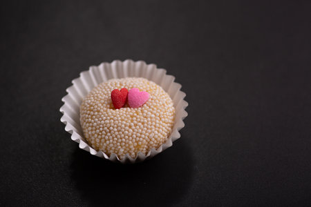 Cupcake with heart shaped sprinkles on black background, closeupの写真素材