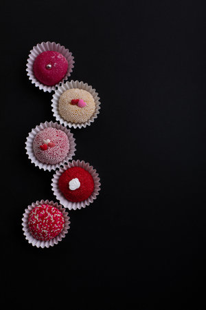 Brigadeiro traditional Brazilian Brasil sweet dessert top view of row of red and white on black backgroundの写真素材