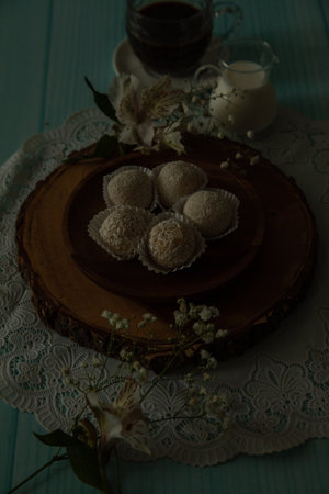 Homemade coconut truffles on a wooden plate with a cup of coffeeの写真素材