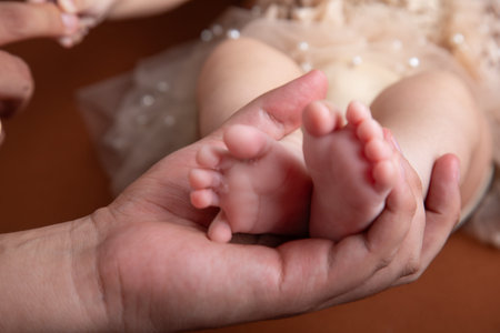 Mother's hands holding the feet of her newborn baby, closeup