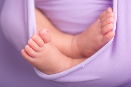 Feet of a newborn baby on a purple background, close-up