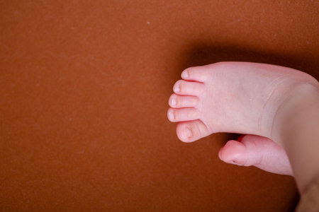 Newborn baby feet on a brown background with copy space for text