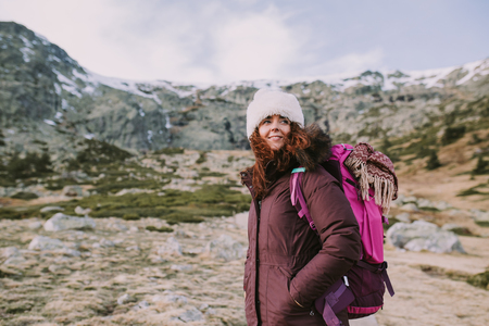 Mountaineer girl with a backpack on her back looks around the high hills and the green meadowsの写真素材
