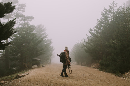 Young woman in the middle of a road looking at the thick fogの写真素材