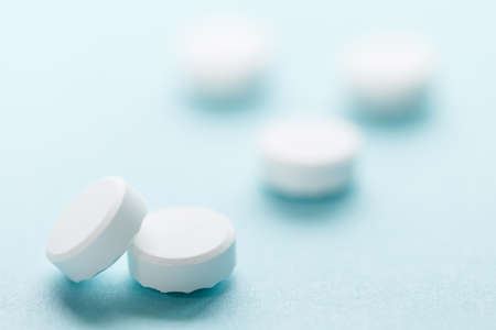 White pills isolated on blue background