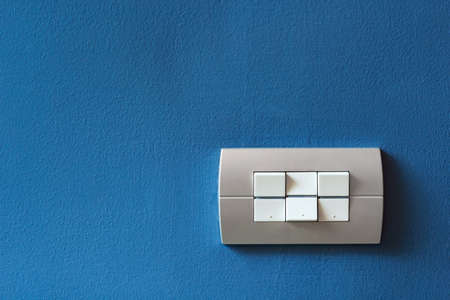 Lighting switch on blue concrete background with copy space