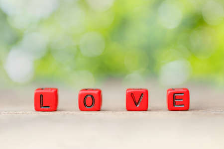 Red block cube with love word on wood table. White blur background. Concept of valentine dayの写真素材