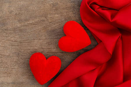 Red satin and two heart on brown wood backgroundの写真素材