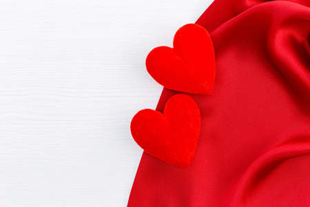 Red satin and two heart on white wood backgroundの写真素材