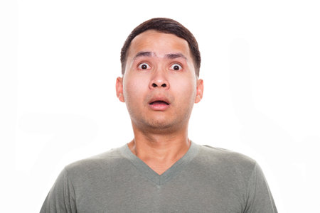 Man wearing casual t-shirt standing shocked with surprise expression over isolated white background