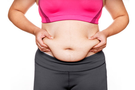 Woman touching his fat belly on white background. Woman hand holding excessive belly fatの写真素材