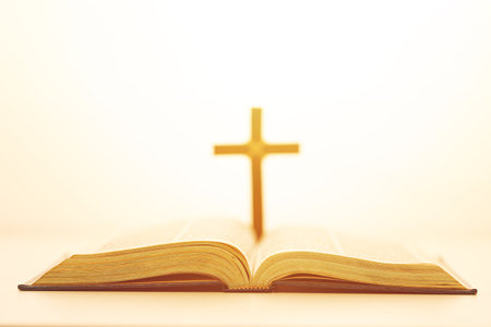 Open Bible with a glowing cross in the background, symbolizing faith, divine guidance, and spiritual...