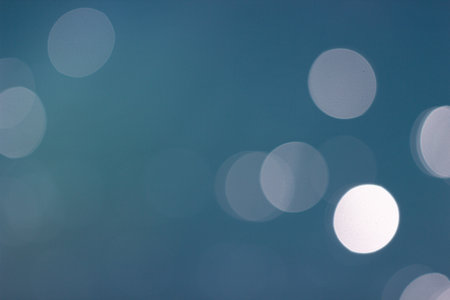 Defocused abstract background of sparkling bokeh lights on calm ocean water in blue tone, ideal for nature, summer, and tranquil design themes.の写真素材
