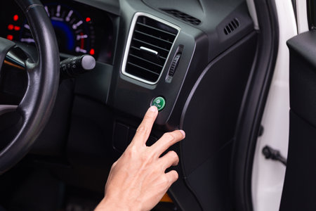 Close-up of a hand pressing the ECON button on a car dashboard, indicating activation of eco mode....