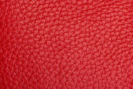 Close-up of red leather texture with detailed grain pattern, ideal for fashion, accessory, or design backgrounds.の写真素材