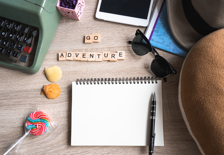 Flat lay top view travel accessories on wooden  background with blank book and Go Adventure words written on wooden block,  travel or vacation concept. Summer background.の写真素材