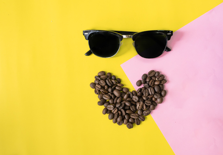 top view flat layer funny face made from coffee beans in smile  icon shape , and sun glasses on two tone multicoloured  backgroundの写真素材